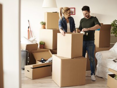 Couple packing stuff among plenty of cardboard boxes